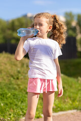 little girl drinking water from bottle in heat. kid suffering from thirst. prevention of dehydration on sunny day. thirsty child drink liquid for hydration, wellness, health. vertical