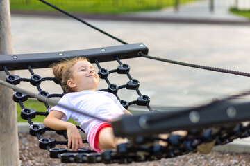 little girl leisure, lies, swinging, resting in hammock. relax urban child in summer city. outdoor recreation kid. happy childhood