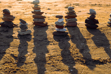 Balanced pebble pyramid silhouette on the beach on sunset with Sea in the background. Zen stones on the sea beach, meditation, spa, harmony, calmness, balance concept.