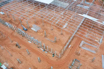Aerial view of busy industrial under construction site workers working with cranes and excavators. Top view of precast concrete slap floor full of steel. Development architecture building.