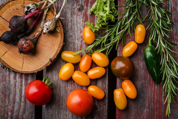 Vegetables yellow cherry tomatoes and red tomatoes on wooden table.
