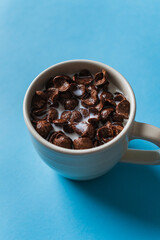 Bowl of chocolate corn flakes cereals with milk on a blue background. Breakfast concept.