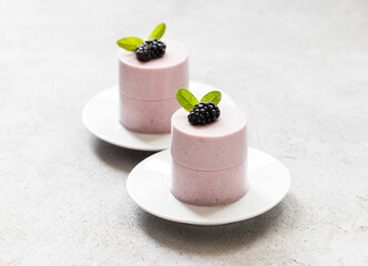 Blackberry cream dessert, Panna Cotta cylindrical shape. On a plate. Light gray background