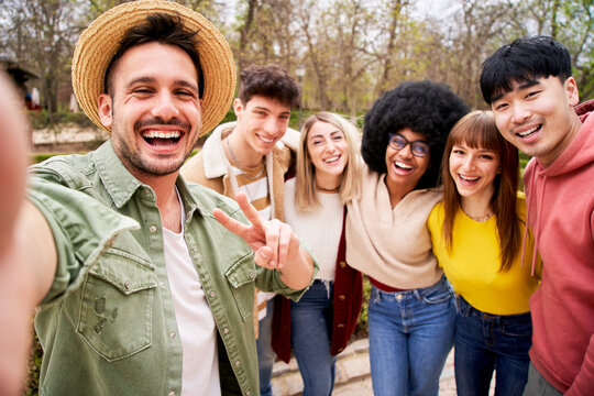 Selfie of group of young friends looking at the camera and laughing a lot. Portrait of multiracial group of students hugging and standing up. 
