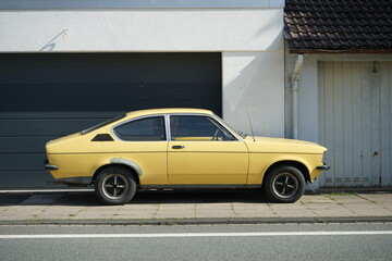 Altes zweitüriges Coupé der Kleinwagen Klasse in hellem Gelb oder Beige der Siebzigerjahre vor einer modernen Garage in Bielefeld im Teutoburger Wald in Ostwestfalen-Lippe