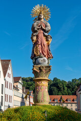 Fototapeta premium Die auf dem Marienbrunnen auf dem Marktplatz von Schwäbisch Gmünd thronende Figur der Mutter Christi, Maria Magdalena, mit Heiligenschein