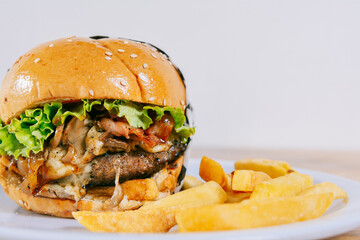 Big cheeseburger with fries served with copy space. Homemade burger with french fries on a plate on wooden table