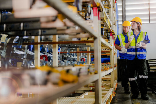 workers checking and inspecting metal machine part items for shipping. male and woman checking the store factory. industry factory warehouse. The warehouse of spare part for machinery and vehicles.