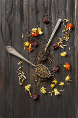 Obraz na płótnie Canvas Dry green and black tea, flower tea on a dark background top view close-up.