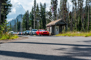 Selective focus on a paved road with a defocused long line of vehicles to enter a national park in...