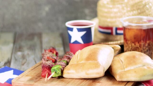 Fiestas Patrias Chile September 18, Independence Day. Empanadas, Anticuchos, mote con huesillo, chicha or wine, Sombrero, huaso, chupallas, straw and emboque, on wooden table with flag and copy space