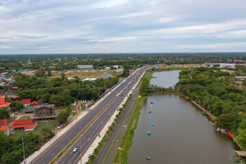 Fototapeta premium Aerial top view of a garden park with green forest trees, river, pond or lake. Nature landscape background, Thailand.