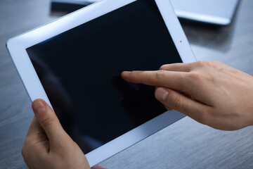 Man using tablet at wooden table, closeup