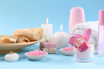 Obraz na płótnie Canvas Retreat concept. Composition with different spa products, burning candles and beautiful orchid on light blue background