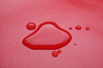 Puddle of water on red background, closeup