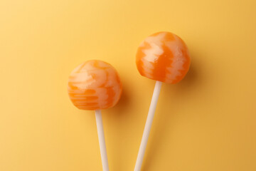 Tasty lollipops on orange background, flat lay