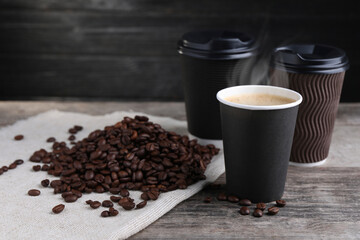 Coffee to go. Paper cups with hot drink and roasted beans on wooden table, space for text
