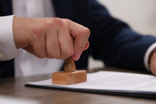 Man stamping document at table, closeup view