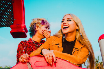 Happy female friends laughing while having fun outdoors.
