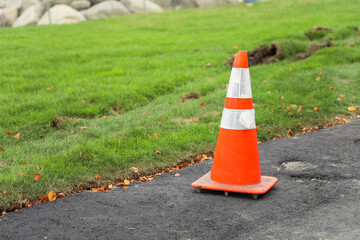 Orange cone on road symbolizes work in progress, caution, temporary disruption, safety measures and...