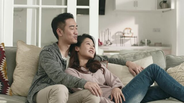 young asian couple sitting on family couch having a pleasant conversation
