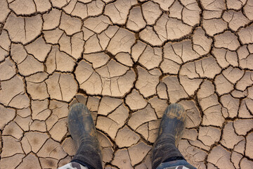 Walking in rubber boots on dry and sun-cracked silt