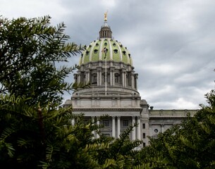 Pennsylvania State Capitol Building Under Cloudy Sky with Plants in Front