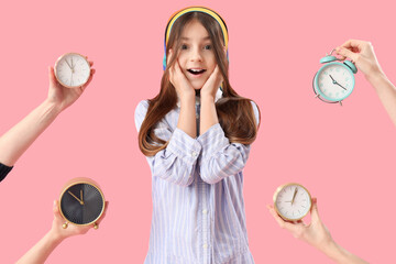 Happy little girl and female hands with alarm clocks on pink background