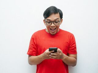 Portrait Indonesian Asian young man shocked looking at smartphone wears red t-shirt for August 17 Indonesia independence day concept