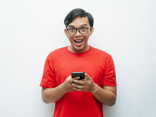 Fototapeta na wymiar Portrait Indonesian Asian young man shocked looking at smartphone wears red t-shirt for August 17 Indonesia independence day concept