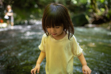 Naklejka premium 渓流で水遊びする小さな女の子