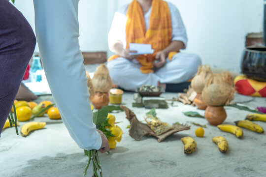 Close-up of a hand placing an offering of flowers in a thanksgiving ritual with a Buddhist priest out of focus