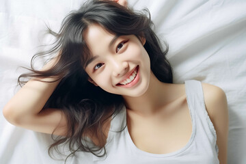 Fototapeta premium Pretty Asian young lady lies on indoor bed. She keeps eyes open and looks satisfied with positive thinking and smiling to camera. Generative AI.