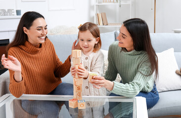 Young lesbian couple and adopted little girl playing with cubes at home