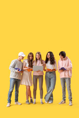Group of students with laptop and copybooks on yellow background