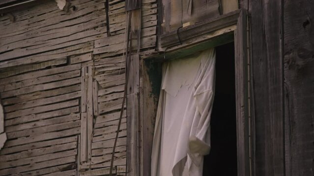 Post apocalyptic abandoned home strewn together with wood plank boards nails and sheet curtain
