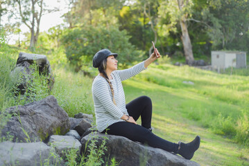 Woman taking a selfie seated on a rock in the middle of nature.