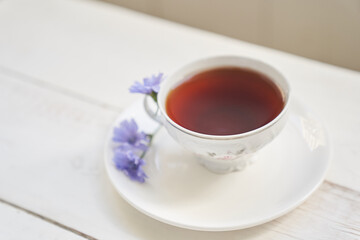 Selective focus on a drink with chicory, cups and saucers on a wooden table with space to copy. A healthy drink made from chicory. High quality photo