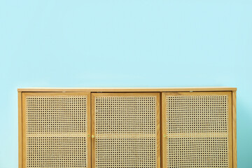 Light wooden chest of drawers near blue wall