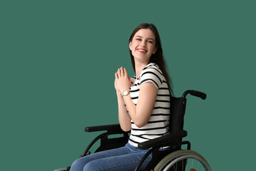 Obraz na płótnie Canvas Happy young woman in wheelchair on green background