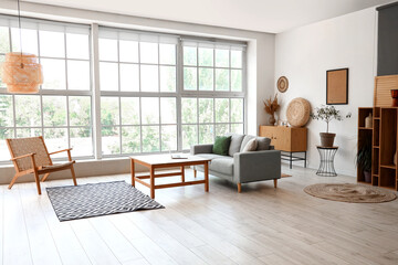 Interior of light living room with sofa, table and armchair
