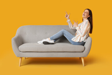 Fototapeta na wymiar Young woman resting on sofa against yellow background
