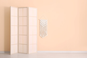 Folding screen and wicker decor near beige wall