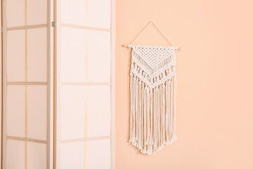Folding screen and wicker decor near beige wall
