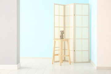 Folding screen, table and figurine near colorful wall