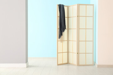 Folding screen and blanket near colorful wall