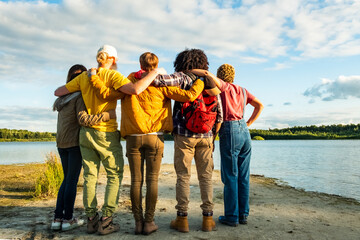 Wanderlust lifestyle, Back view of group of young multi racial friends camping standing hugging on...