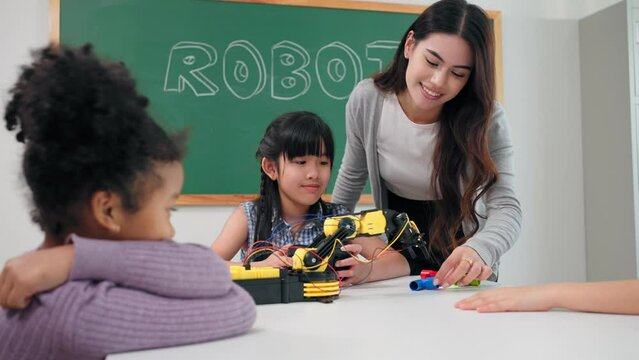 Smart primary students grouping to learning robot free electives with female teacher in classroom. Teacher female teach children assemble robot in science subject at elementary school.