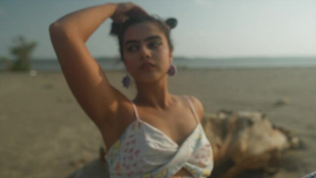 Cinematic close-up shot in slow motion of an Indian fashion model posing on a sandy beach in Goa India, Slomo