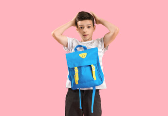 Portrait of shocked schoolboy with backpack on pink background